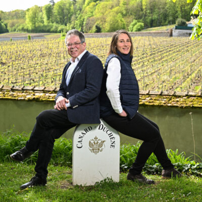 Cynthia Fossier et Laurent Fédou se tiennent devant un paysage de vignes.