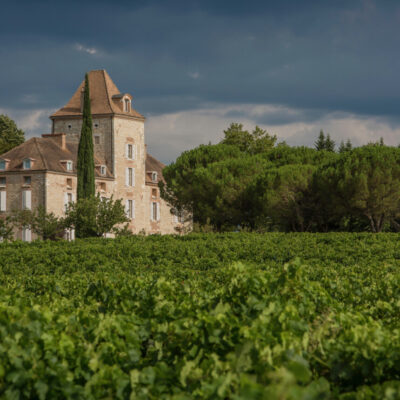 Château de Haute-Serre entouré de vignes avec un ciel chargé