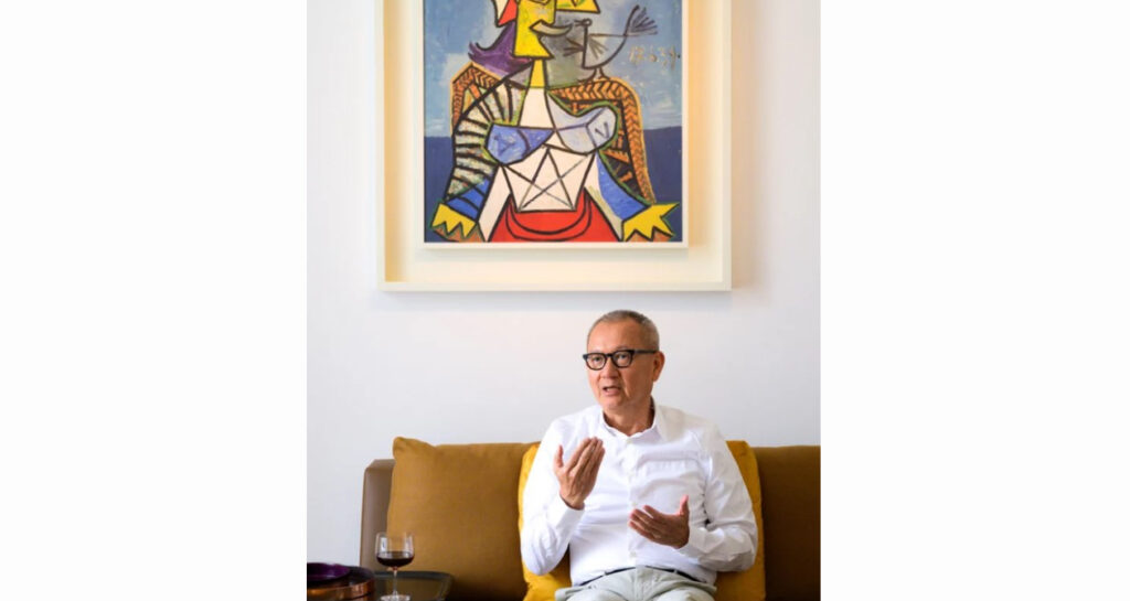 Pierre Chen assis sur un capé devant une oeuvre d'art de Picasso