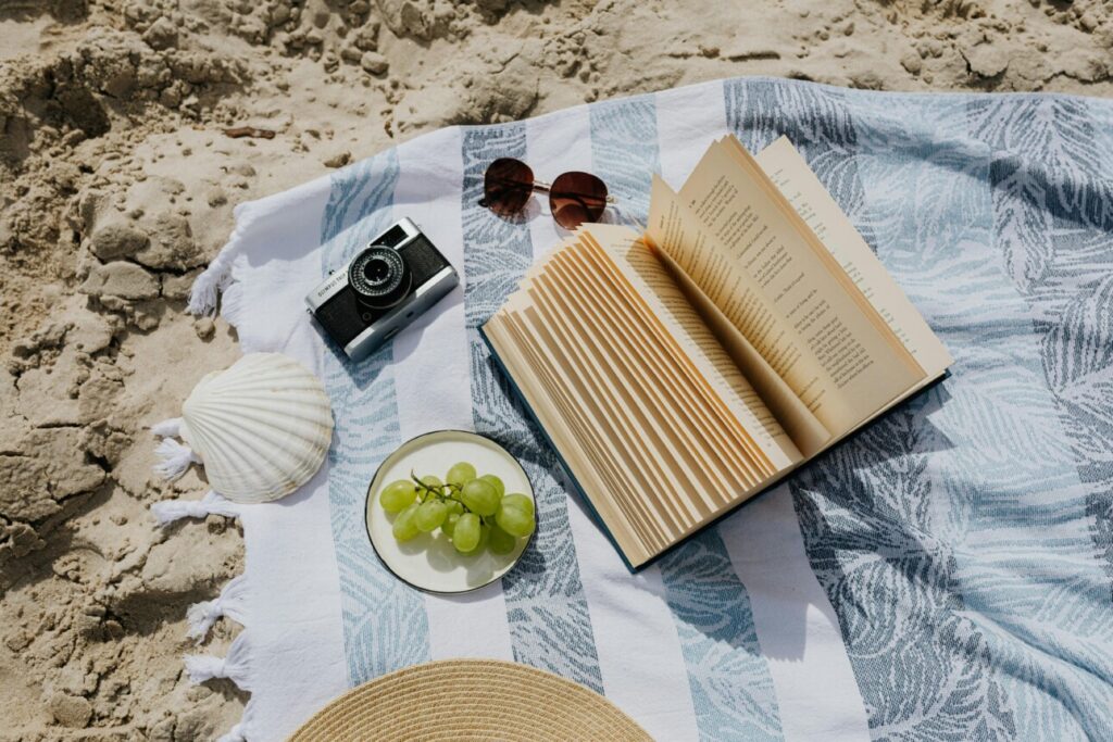 livre sur la plage avec raisin et chapeau