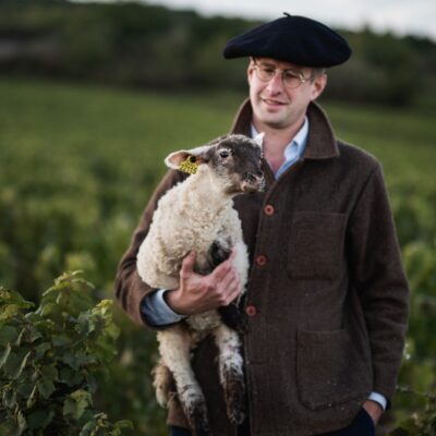 Armand Heitz dans ses vignes avec un agneau dans les bras